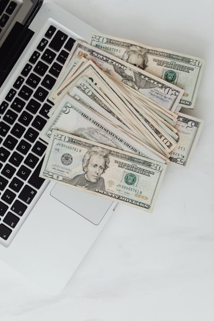 US dollar banknotes scattered over a laptop, symbolizing online finance and digital banking.